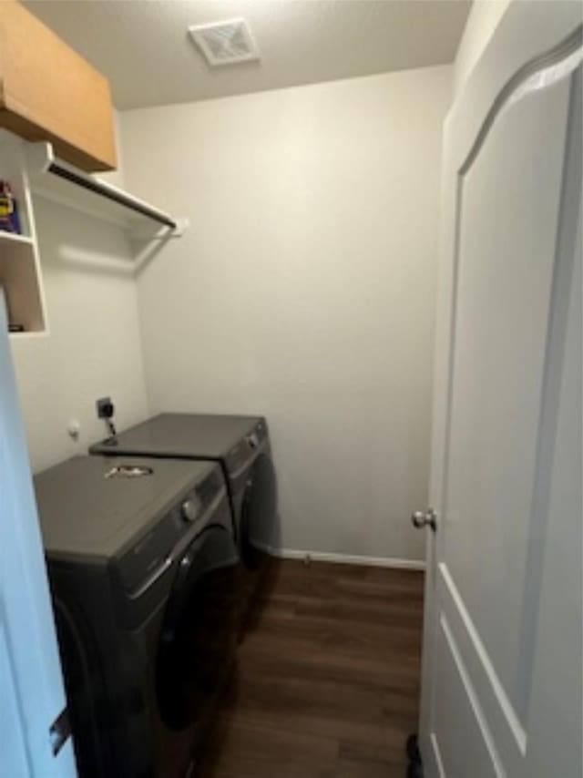 laundry area featuring washing machine and clothes dryer, visible vents, baseboards, wood finished floors, and laundry area