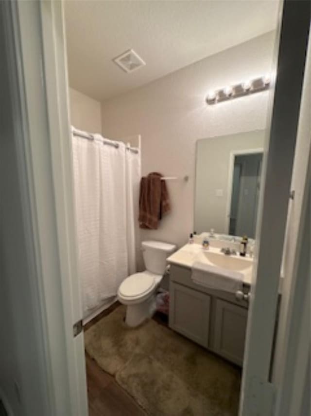 full bath with visible vents, toilet, curtained shower, and vanity