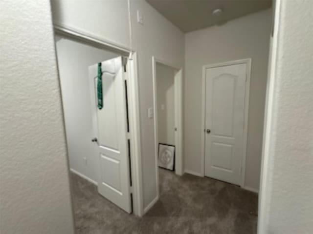 corridor with carpet flooring and a textured wall