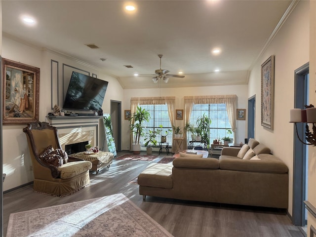 living area featuring visible vents, a high end fireplace, ornamental molding, wood finished floors, and a ceiling fan