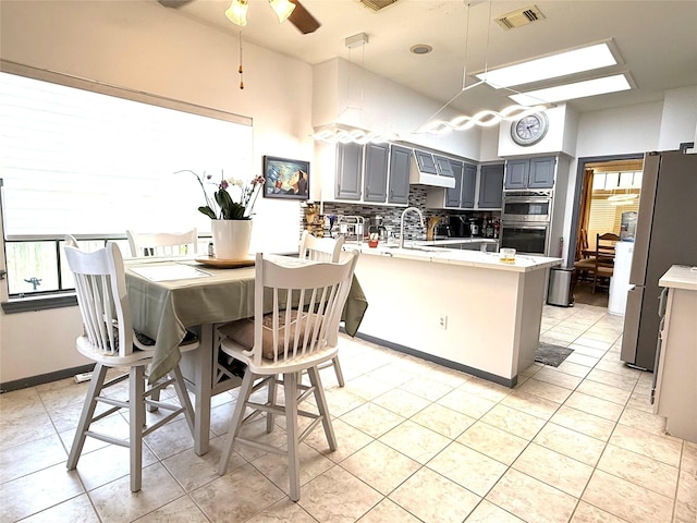 7615 Clover Canyon Cir, Houston, TX 77095 - kitchen featuring a peninsula, appliances with stainless steel finishes, gray cabinets, extractor fan, and backsplash