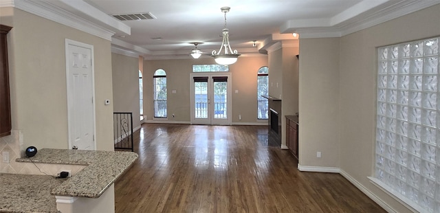 foyer featuring ornamental molding, baseboards, dark wood-style floors, visible vents, and a fireplace