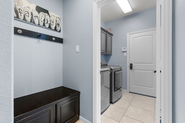 washroom with independent washer and dryer, cabinet space, and light tile patterned floors