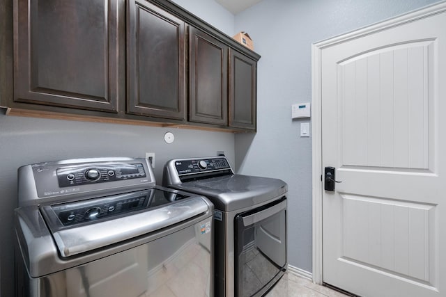 clothes washing area featuring light tile patterned floors, cabinet space, and washer and dryer