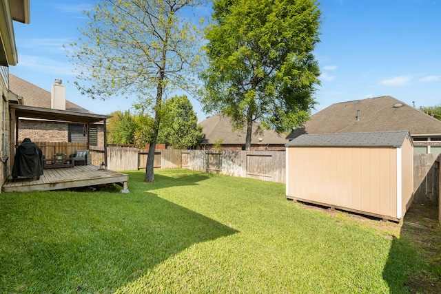 view of yard with an outbuilding, a storage unit, a fenced backyard, and a wooden deck