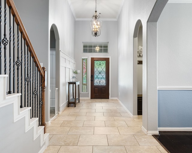 foyer entrance featuring baseboards, arched walkways, stairway, and light tile patterned floors