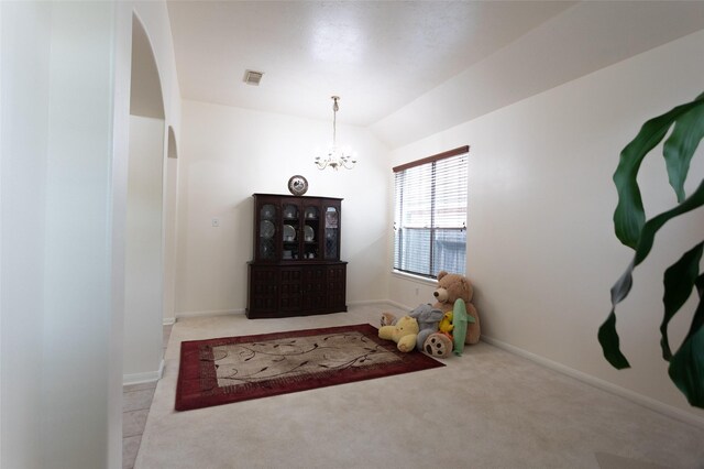 entrance foyer with arched walkways, light colored carpet, a chandelier, vaulted ceiling, and baseboards