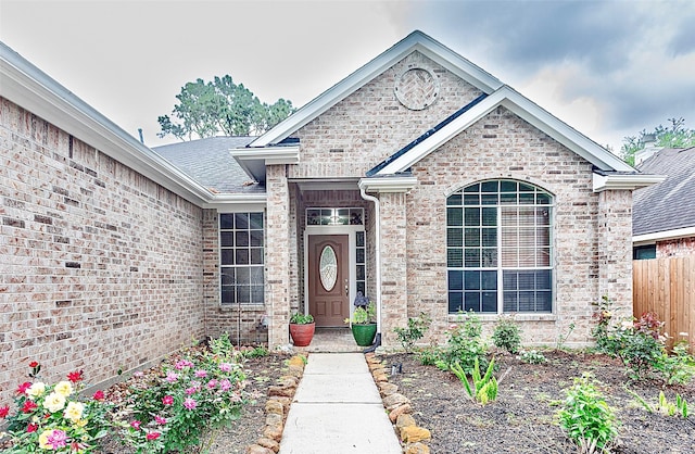 property entrance featuring fence and brick siding