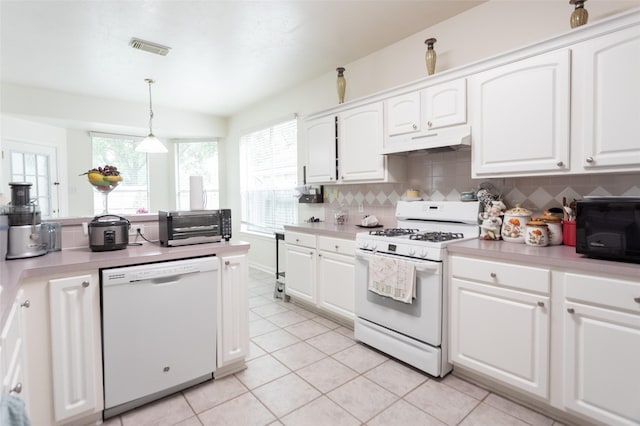 kitchen featuring white appliances, under cabinet range hood, light tile patterned flooring, and white cabinetry