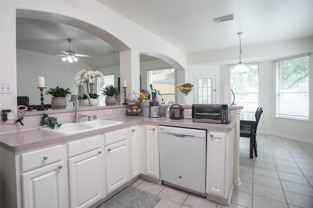 kitchen with dishwasher, a sink, light tile patterned floors, a peninsula, and plenty of natural light