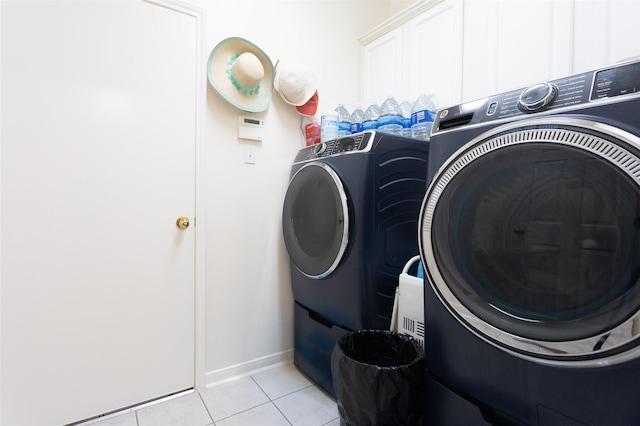 clothes washing area with washer and dryer, light tile patterned floors, and baseboards