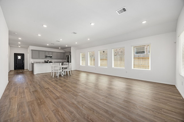 unfurnished living room with dark wood finished floors, baseboards, visible vents, and recessed lighting