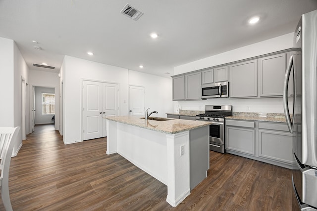 kitchen with stainless steel appliances, visible vents, gray cabinets, a sink, and a center island with sink