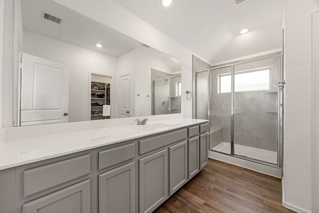 bathroom featuring wood finished floors, a stall shower, a spacious closet, vanity, and visible vents