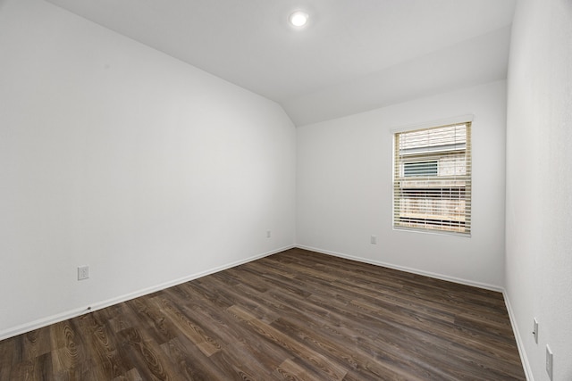 unfurnished room featuring lofted ceiling, dark wood-style floors, and baseboards