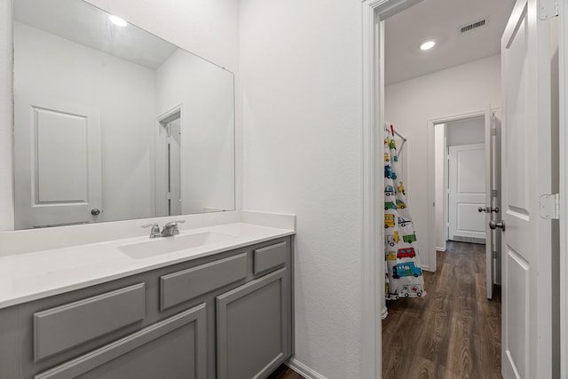 full bath featuring wood finished floors, vanity, curtained shower, baseboards, and visible vents