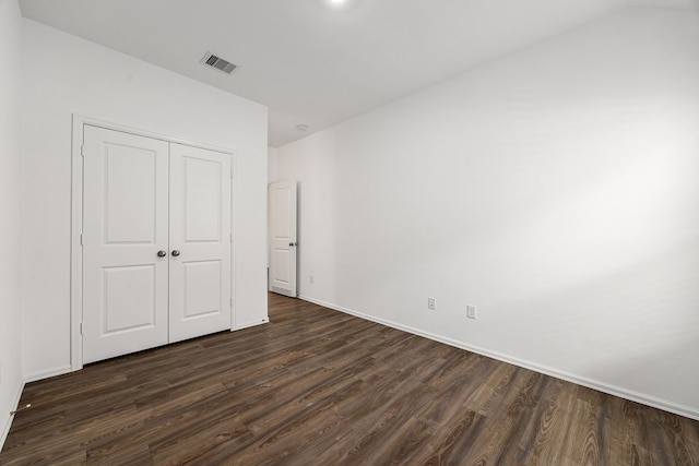 unfurnished bedroom featuring baseboards, a closet, dark wood-style floors, and visible vents