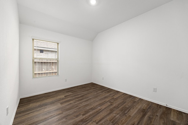 empty room featuring baseboards, lofted ceiling, and dark wood-style floors