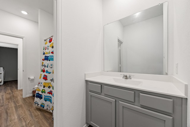 full bath with a shower with shower curtain, wood finished floors, and vanity