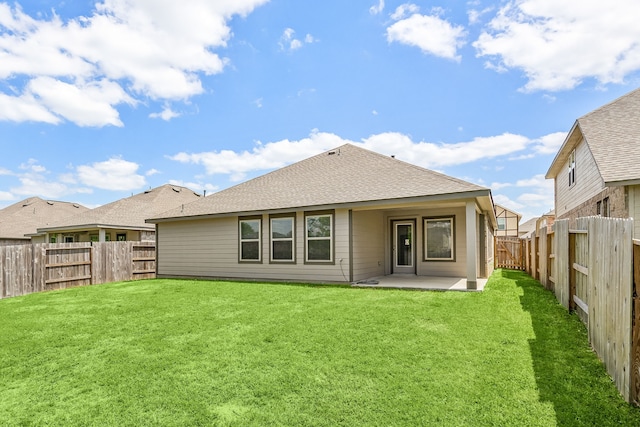 rear view of house with a patio area, a lawn, a shingled roof, and a fenced backyard