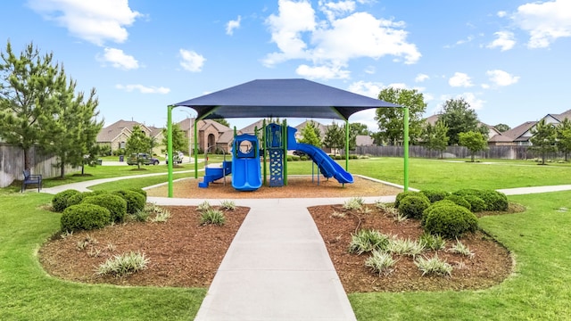 community playground with fence, a lawn, and a residential view