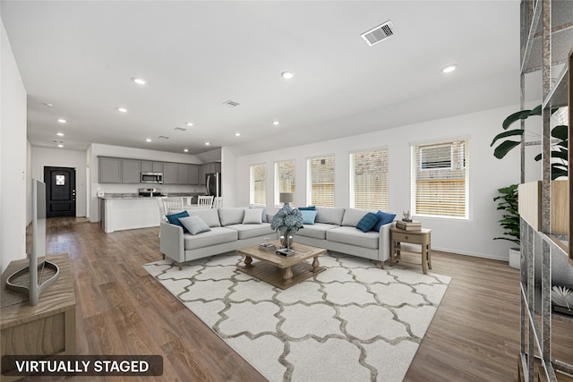 living area featuring baseboards, wood finished floors, visible vents, and recessed lighting