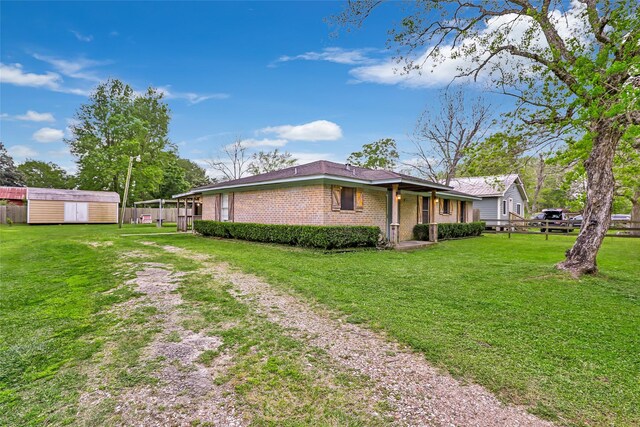 507 E Linney St, Dayton, TX 77535 - view of property exterior featuring an outdoor structure, a shed, fence, driveway, and a lawn