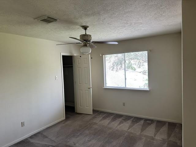 unfurnished bedroom featuring baseboards, visible vents, a textured ceiling, and carpet flooring