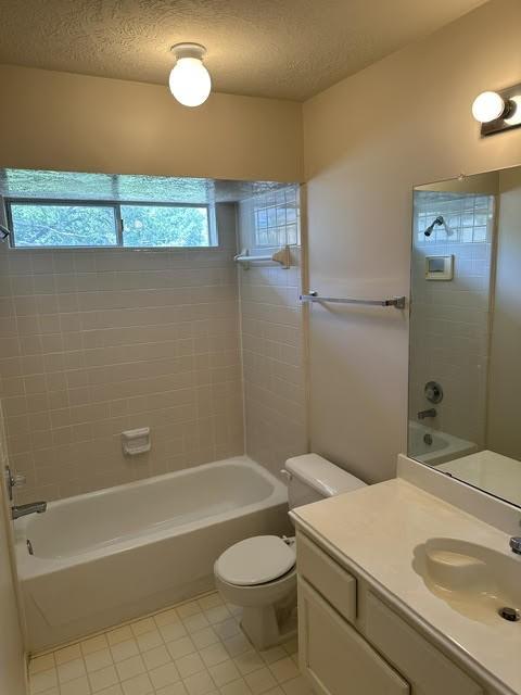 bathroom featuring tile patterned flooring, bathtub / shower combination, toilet, vanity, and a textured ceiling