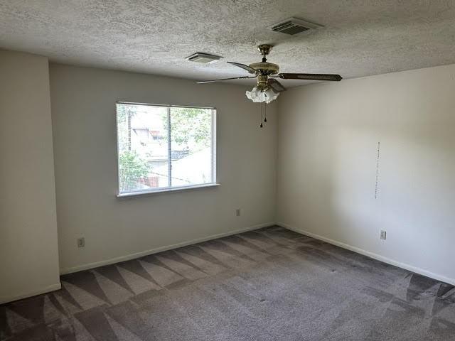 empty room with baseboards, visible vents, ceiling fan, and carpet flooring