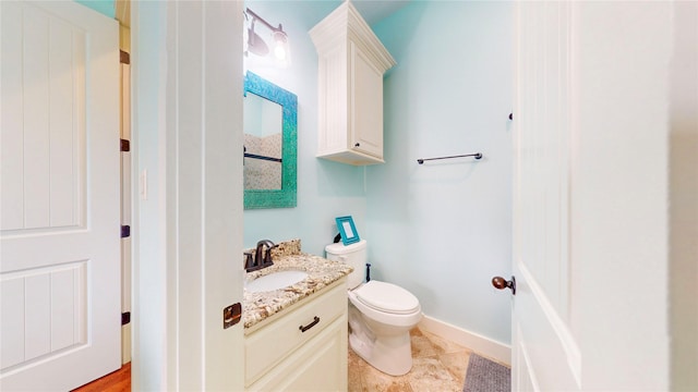 half bathroom featuring toilet, vanity, and baseboards