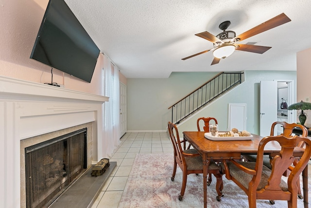 6506 Kentwick Dr, Houston, TX 77084 - dining space featuring stairs, a ceiling fan, a fireplace, a textured ceiling, and light tile patterned floors