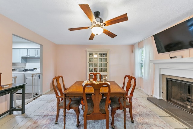 6506 Kentwick Dr, Houston, TX 77084 - dining room featuring baseboards, a fireplace with raised hearth, ceiling fan, separate washer and dryer, and light tile patterned floors
