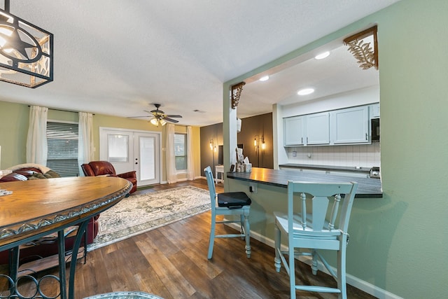 6506 Kentwick Dr, Houston, TX 77084 - kitchen with a breakfast bar, decorative backsplash, dark countertops, ceiling fan, and dark wood-type flooring