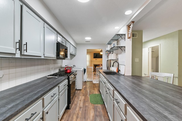 6506 Kentwick Dr, Houston, TX 77084 - kitchen with gas range, dark wood-type flooring, a sink, dark countertops, and black microwave
