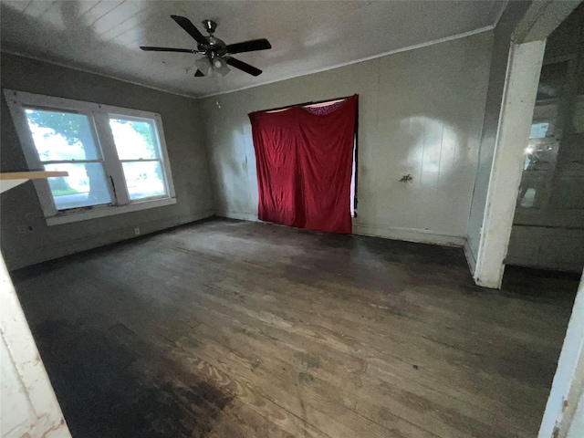 empty room with crown molding, baseboards, ceiling fan, and wood finished floors