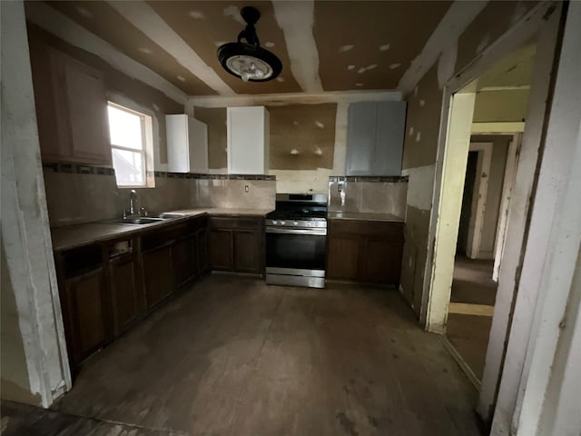 kitchen featuring light countertops, a sink, stainless steel gas stove, and decorative backsplash