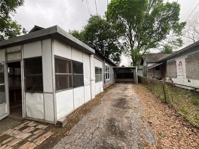 view of home's exterior with a sunroom, driveway, and fence