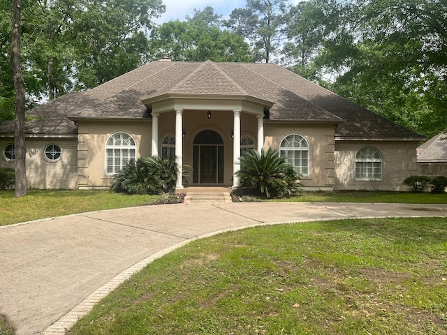 5 Briarwood Dr, Conroe, TX 77301 - greek revival house with a shingled roof, a front yard, and stucco siding