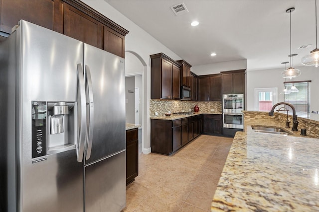 kitchen with tasteful backsplash, dark brown cabinets, visible vents, appliances with stainless steel finishes, and a sink