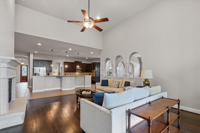living room with high vaulted ceiling, ceiling fan, dark wood-type flooring, recessed lighting, and baseboards