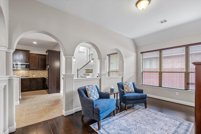 sitting room with a healthy amount of sunlight, lofted ceiling, visible vents, and wood finished floors
