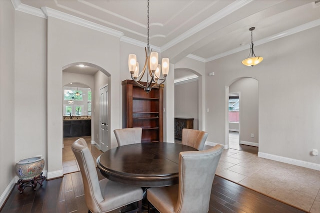 dining area featuring arched walkways, wood finished floors, an inviting chandelier, and baseboards