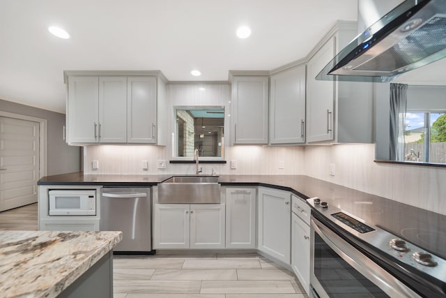 kitchen featuring ventilation hood, recessed lighting, dark stone countertops, a sink, and stainless steel appliances