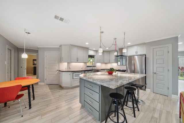 kitchen with white microwave, freestanding refrigerator, visible vents, gray cabinets, and a center island
