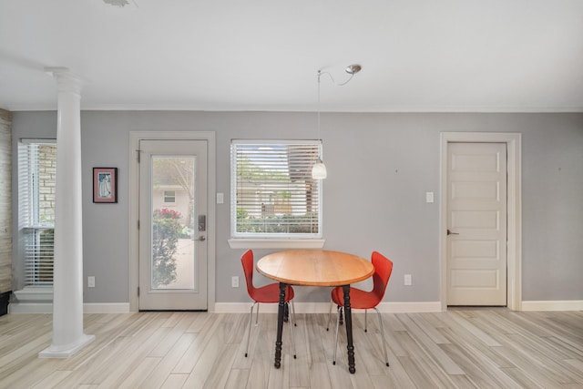 dining space with baseboards, ornate columns, ornamental molding, and wood finished floors