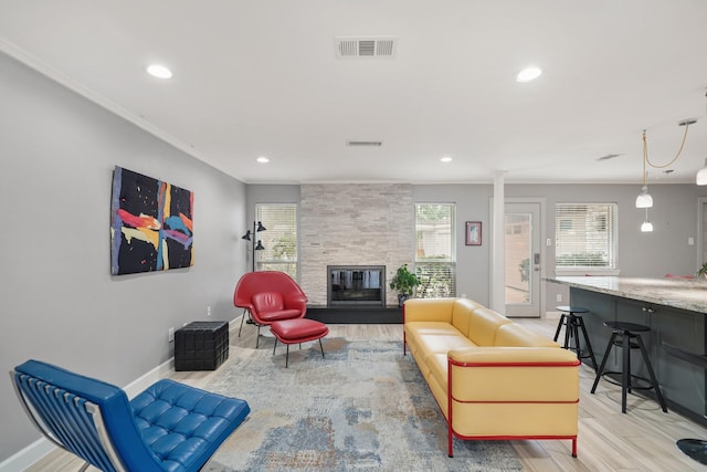 living room with crown molding, visible vents, and light wood-type flooring