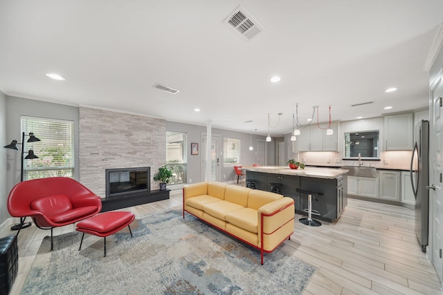 living area with visible vents, a stone fireplace, and light wood-type flooring
