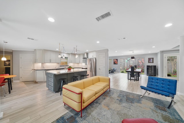living room featuring light wood-style floors, recessed lighting, visible vents, and baseboards