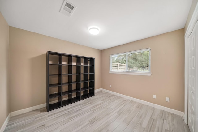 unfurnished bedroom featuring wood finished floors, baseboards, a closet, and visible vents